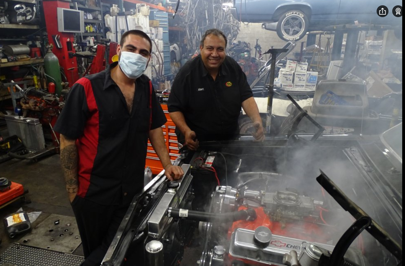 Albert and a coworker working on an engine together